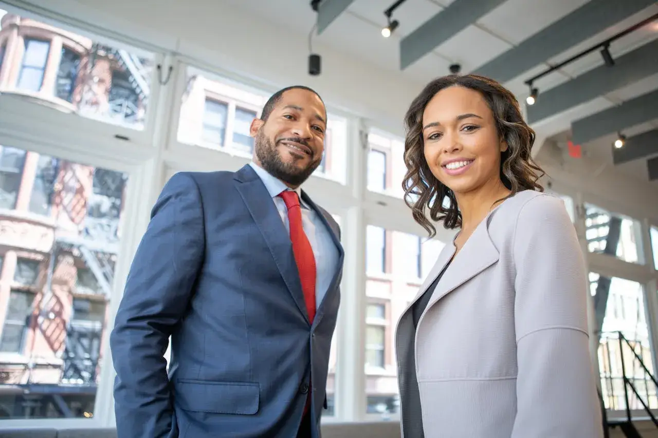 Two confident business professionals smiling in modern office setting