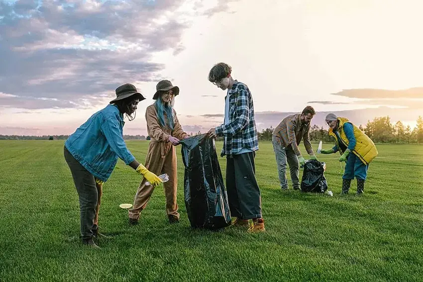 Group of people cleaning up litter in a park during community service event