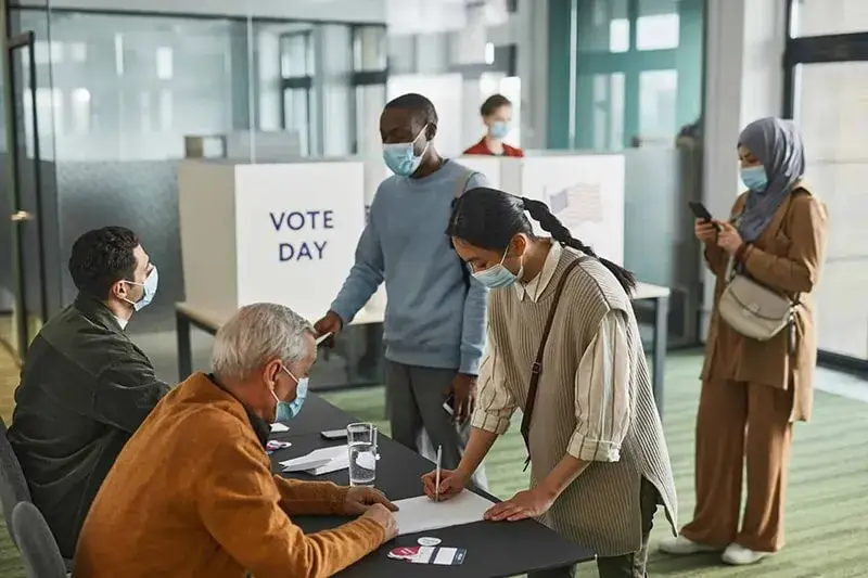People wearing masks registering and voting at polling station on election day